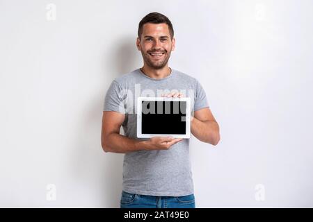 Studio shot of happy man holding a ipad with black empty blank screen. - Image Stock Photo