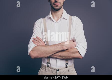 Cropped photo of macho business man arms crossed hiding half face strong hands dressed formalwear white shirt beige suspenders pants isolated grey Stock Photo