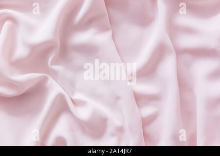 Pink wrinkled silk fabric. The pink fabric is laid out waves. Pink fabric background or texture. Stock Photo