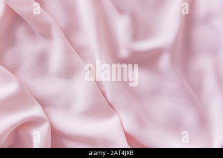 Pink wrinkled silk fabric. The pink fabric is laid out waves. Pink fabric background or texture. Stock Photo