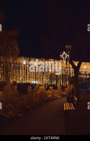 Orange lights in the park, Christmas decorations and an empty bank. Stock Photo