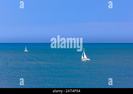 Two yachts far out at sea on a sunny day. Stock Photo