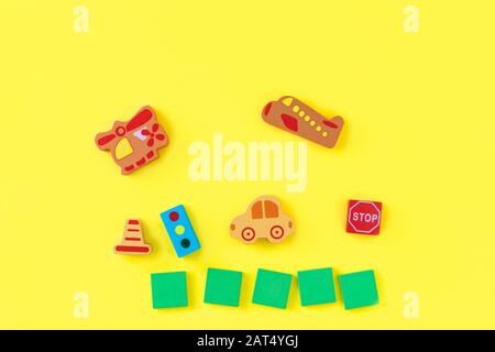 Colorful developing wooden blocks and handmade cars on yellow background. Natural, eco-friendly wooden toys for children. Top view. Flat lay. Copy space. Stock Photo