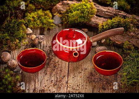 Tea time concept. Red ceramic teapot and cups, against wooden background. Stock Photo