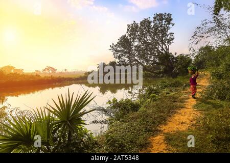 Rural India landscape with unpaved village road and pond at sunrise Stock Photo