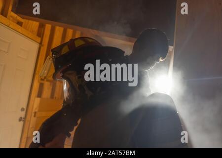 Firefighter carrying the kid on his shoulders from the burning house Stock Photo