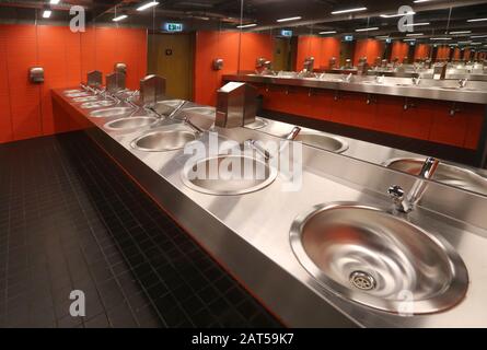 Cracow. Krakow. Poland. Sink row, stainless steel basins and mirrors in public mens room. Stock Photo