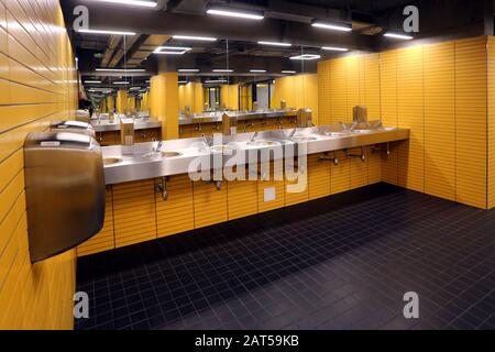 Cracow. Krakow. Poland. Sink row, stainless steel basins and mirrors in public mens room. Stock Photo