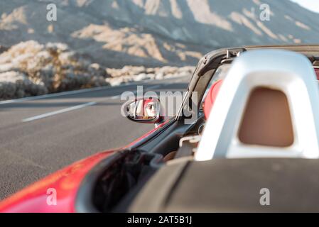 Woman driving convertible car on the beautiful desert road, view from the backside Stock Photo