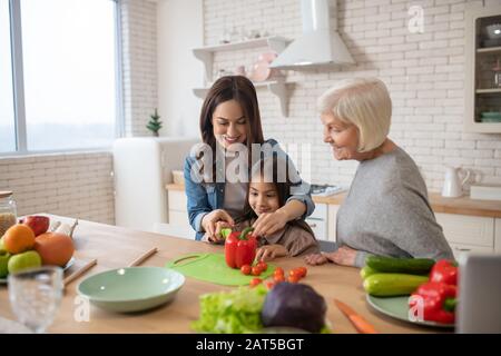 Smiling mom, daughter and grandmother making breakfast. Stock Photo