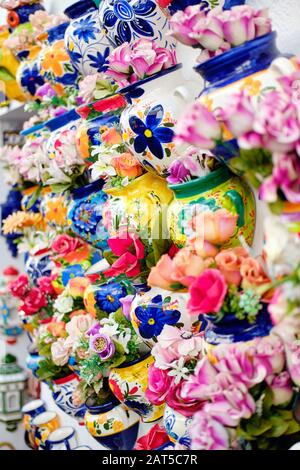 Vertical full frame image close up view background hanging on wall decorative handmade flowerpots with artificial flowers, Mijas village, Spain Stock Photo