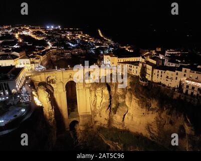 Aerial photo drone point of view huge gorge and ancient architecture, city street lights night view of Ronda in Spanish province of Málaga. Spain Stock Photo