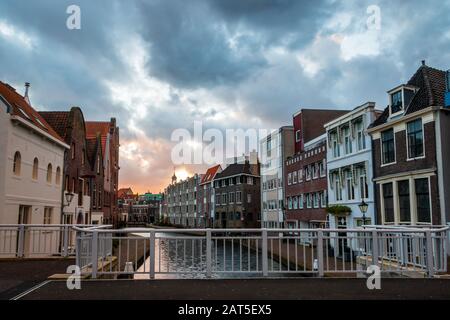 The center of Schiedam with beautiful narrow streets and small canals, photo taken in the evening hours with beautiful orange and blue clouds. Provinc Stock Photo