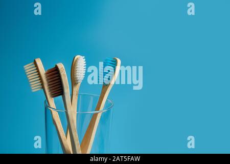 Wooden toothbrushes with a glass cup on a blue background with copy space. Environmental awareness, pollution Stock Photo