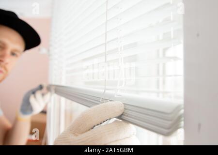 Construction worker man install blinds on plastic white upvc windows in house Stock Photo