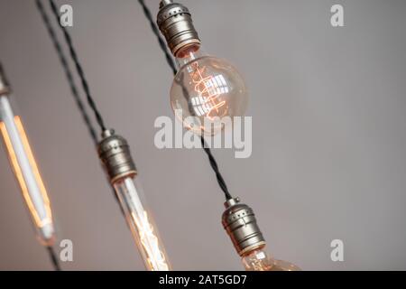 Edison retro lamp incandescent bulbs on gray plaster wall background in loft. Concept Vintage style. Copy space Stock Photo