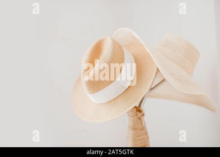 Straw yellow hat hanging on a white wooden coat hanger, scandinavian style minimalism. Travel concept Stock Photo