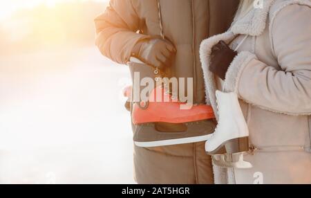 Close-up of ice skates for rink are held guy and girl friends on background of winter and snow Stock Photo