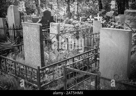 In the old cemetery there are graves with tombstones and crosses. Black and white image. Stock Photo