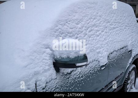 Close-up of a car under the snow. Winter season and seasonal specific. Car covered in snow closeup. Stock Photo