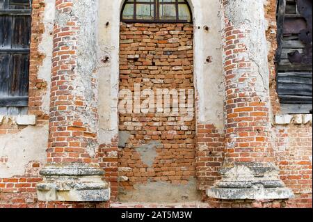 wall of an abandoned building, the entrance to which is bricked up, and the windows are boarded up Stock Photo