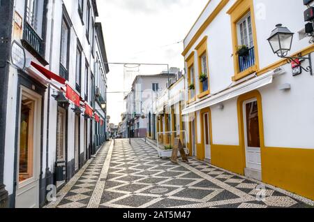 Ponta Delgada, Azores, Portugal - Jan 12, 2020: Empty street with bars and restaurants in the historical center of the Portuguese city. Colorful facades, traditional houses, cobbled street. Overcast. Stock Photo