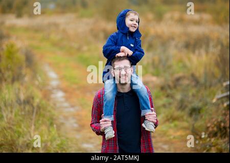 The son sits on his dad s shoulders. Walking in the country. Copy space Stock Photo
