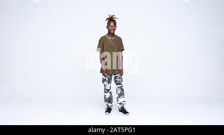 Smiling african man standing isolated on white background. Young man in casual clothes with dreadlocks tied together. Stock Photo