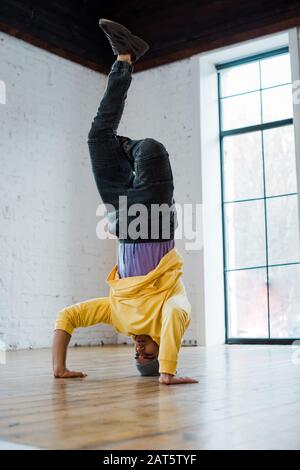 man in hat breakdancing and doing handstand in dance studio Stock Photo
