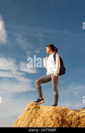 woman with backpack on the top of the rock and enjoying view, trekking, lifestyle. Stock Photo