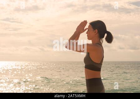 Woman Meditating by the ocean, Yoga Poses Prayer To The Third Eye Stock Photo