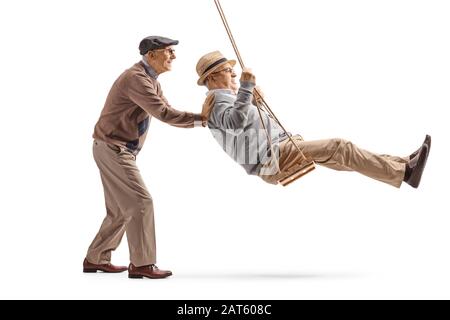 Full length profile shot of senior man pushing his friend on a swing isolated on white background Stock Photo