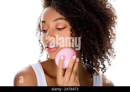 beautiful african american girl using silicone cleansing facial brush, isolated on white Stock Photo