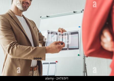 Cropped view of smiling designer presenting wireframe sketches for mobile website to colleague in designer studio Stock Photo