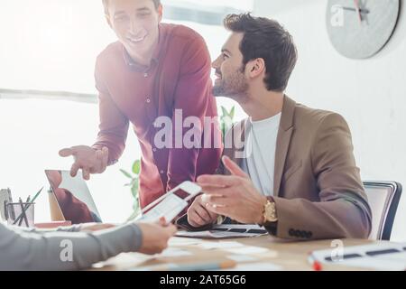 Selective focus of smiling designers working with wireframe sketches of mobile website at table Stock Photo