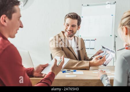 Selective focus of smiling designers developing mobile app interface in designer studio Stock Photo