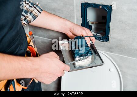 cropped view of workman holding screwdriver near toilet Stock Photo