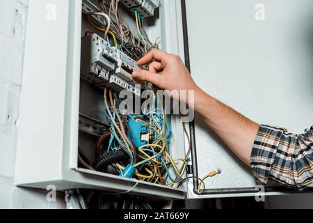 cropped view of electrician touching switch on switchboard Stock Photo