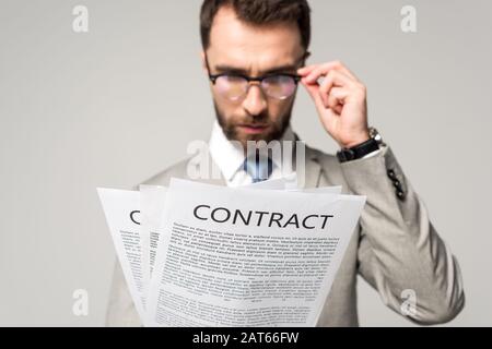 serious businessman in glasses looking at contracts isolated on grey Stock Photo