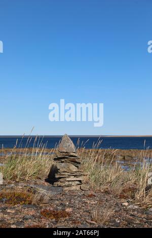 Single Inukshuk or Inuksuk along the arctic coast near Arviat, Nunavut Stock Photo