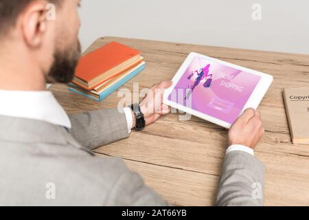 cropped view of businessman using digital tablet with online shopping app on screen isolated on grey Stock Photo