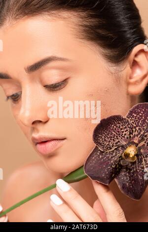 woman with problem skin holding orchid near face isolated on beige Stock Photo