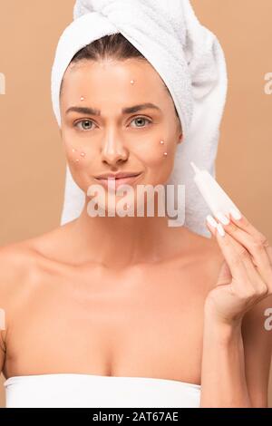 smiling girl with acne on face holding treatment cream isolated on beige Stock Photo