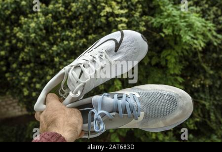 Paris, France - Sep 23, 2019: Male hand POV holding professional running shoes manufactured by Nike comparing two Odyssey React Flyknit 2 and Zoom Rival Fly for women Stock Photo