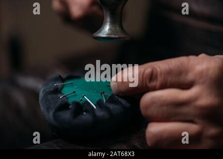 cropped view of cobbler fixing leather to shoe with nails in workshop Stock Photo