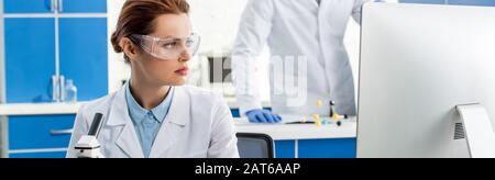 panoramic shot of attractive molecular nutritionist looking at computer Stock Photo