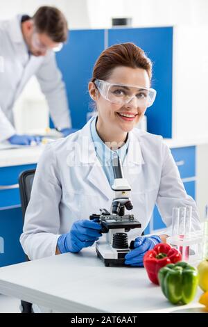 selective focus of smiling molecular nutritionist looking at camera Stock Photo