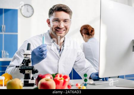 selective focus of smiling molecular nutritionist holding test tube Stock Photo