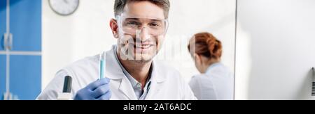 panoramic shot of smiling molecular nutritionist holding test tube Stock Photo