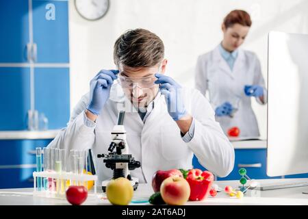 molecular nutritionist in goggles looking at microscope in lab Stock Photo